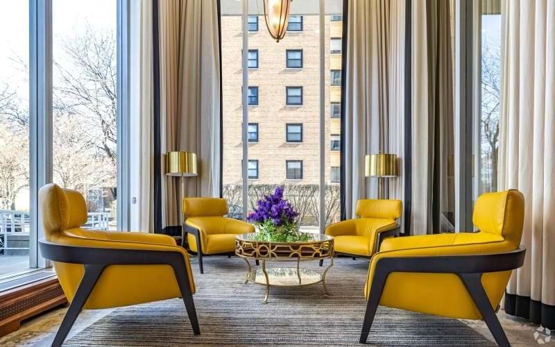 a room with yellow chairs and a table with a lamp on it